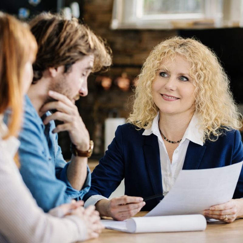 Insurance company president Vilma Jaruliene consulting with clients at a desk, reviewing documents together in a modern office setting.